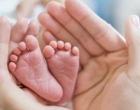 Des petits pieds de bébé dans des mains adulte